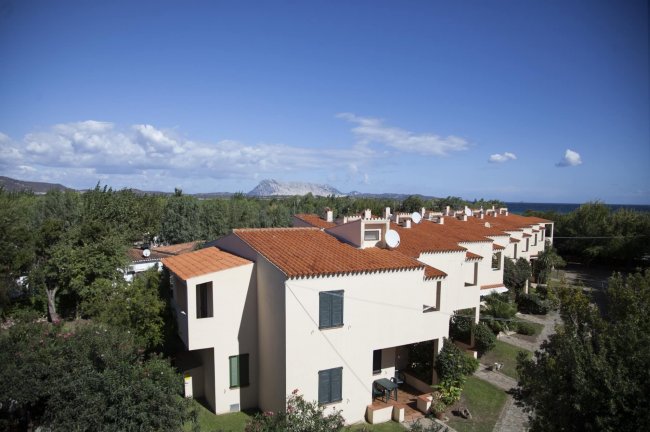 Complesso residenziale con tetti rossi e paesaggio collinare sullo sfondo.