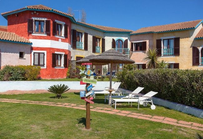 Edificio colorato con giardino e sedie a sdraio.