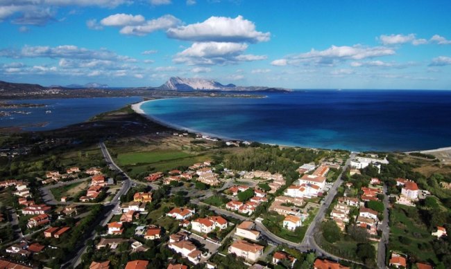 Vista aerea di una costa con mare blu e case.