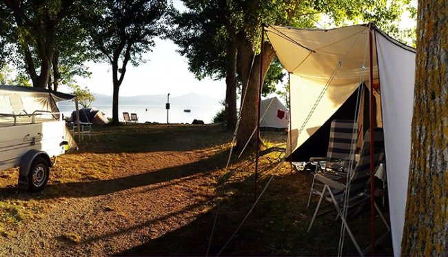 Un campeggio con tende vicino a un lago.