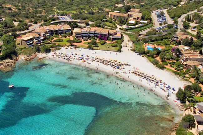 Spiaggia con mare turchese e ombrelloni, vista aerea.