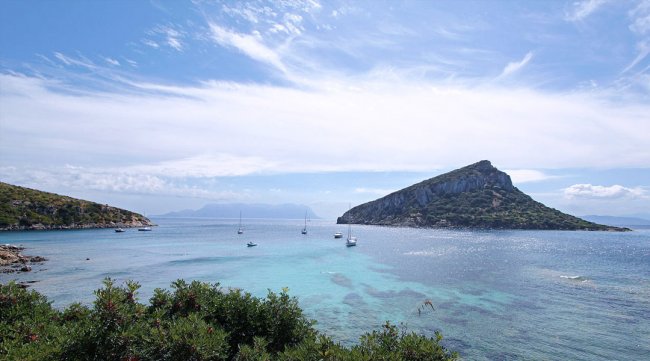 Baia con mare cristallino e barche ormeggiate.