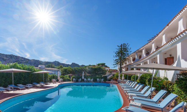 Piscina con lettini e ombrelloni al sole.