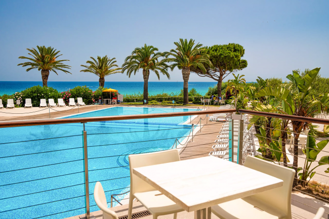 Tavolo vista piscina, mare e palme.