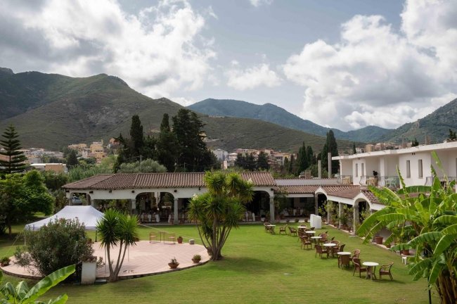 Un giardino curato con edifici e montagne sullo sfondo.