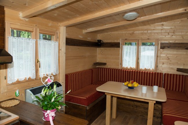 Interno di una cabina in legno con tavolo e sedute rosse.