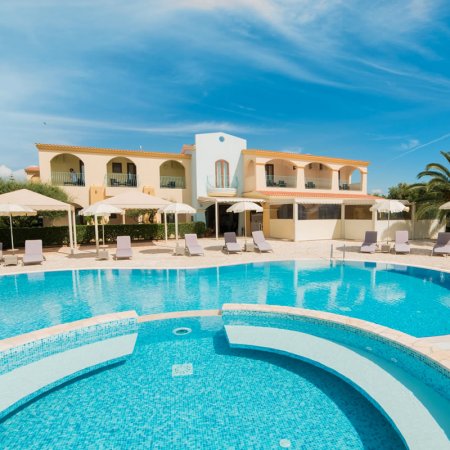 Piscina con lettini e edificio sullo sfondo.