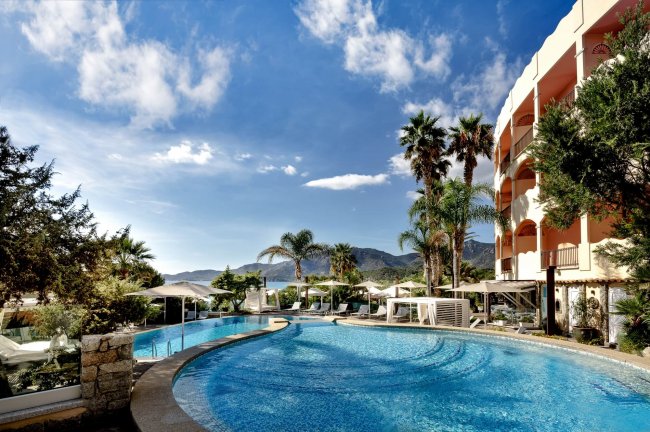 Ampia piscina con hotel e palme.