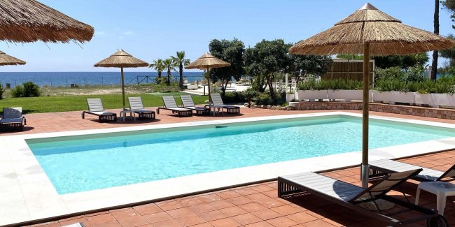 Una piscina con lettini e ombrelloni, vista mare.