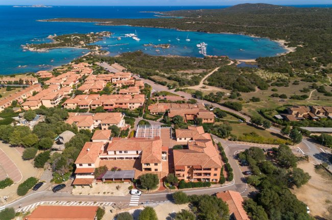 Veduta aerea di edifici e una baia con barche.