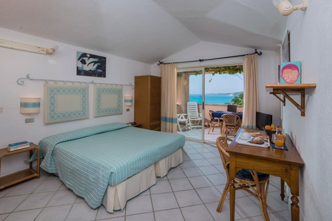 Camera da letto con letto matrimoniale, vista mare, scrivania e terrazza.