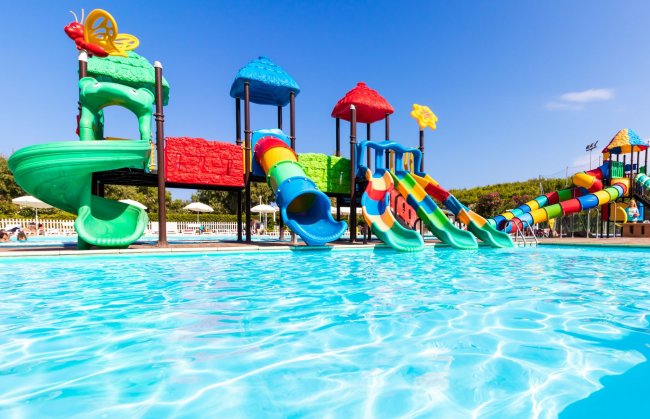 Parco acquatico con scivoli colorati e piscina limpida.