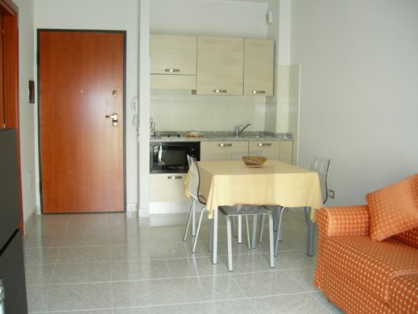 Cucina compatta con tavolo e divano arancione.