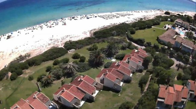 Vista dall'alto di case e spiaggia con mare blu.