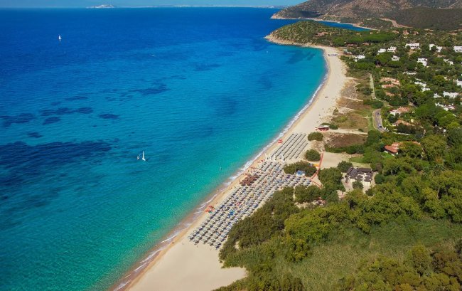 Spiaggia con mare blu e ombrelloni.