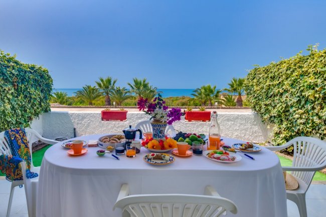 Tavola apparecchiata per colazione all'aperto con vista mare.