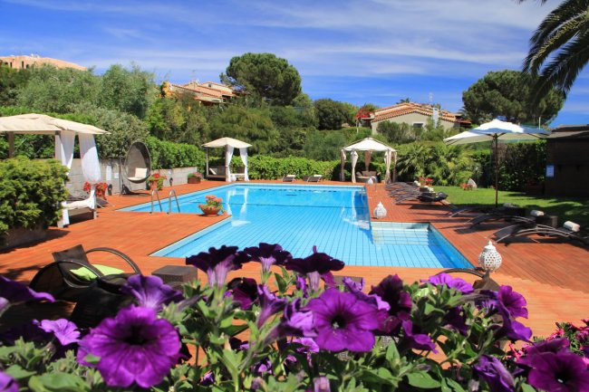 Piscina circondata da giardino e fiori viola.