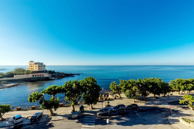 Vista mare con alberi e strada costeggiante.