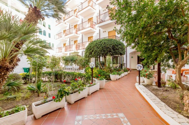 Giardino con piante e balconi sullo sfondo.