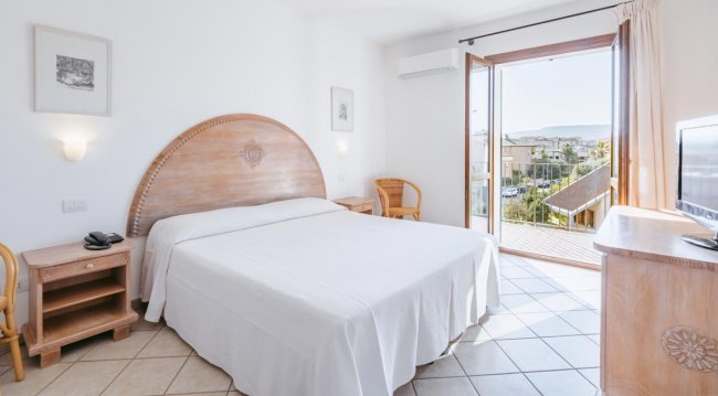 Camera con letto matrimoniale e balcone soleggiato.