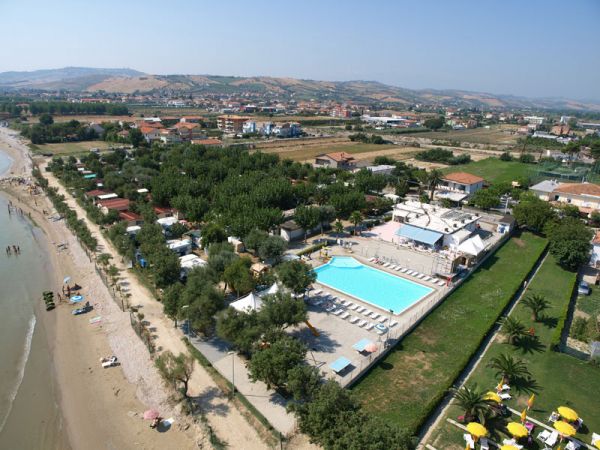 Vista aerea di un complesso con piscina vicino alla spiaggia e aree verdi.
