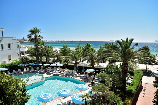 Piscina circondata da palme e vista spiaggia.