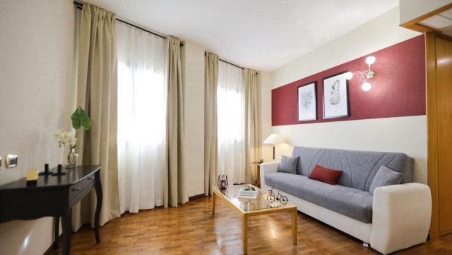 Soggiorno con divano, tavolino e quadro alle pareti.