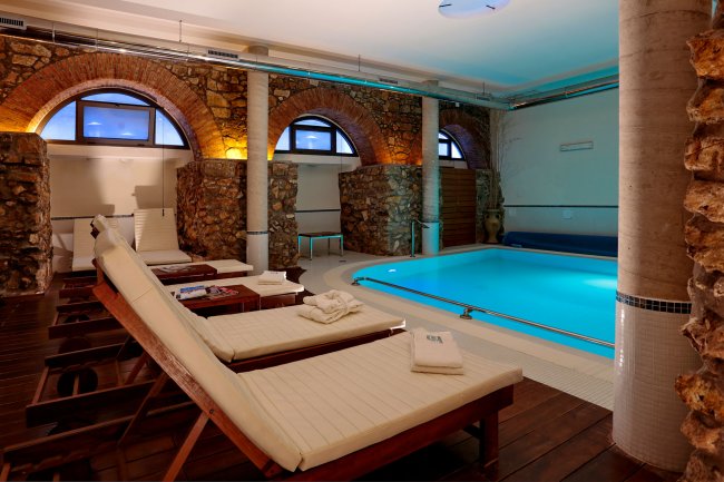 Spa con piscina, lettini e arcate in pietra.