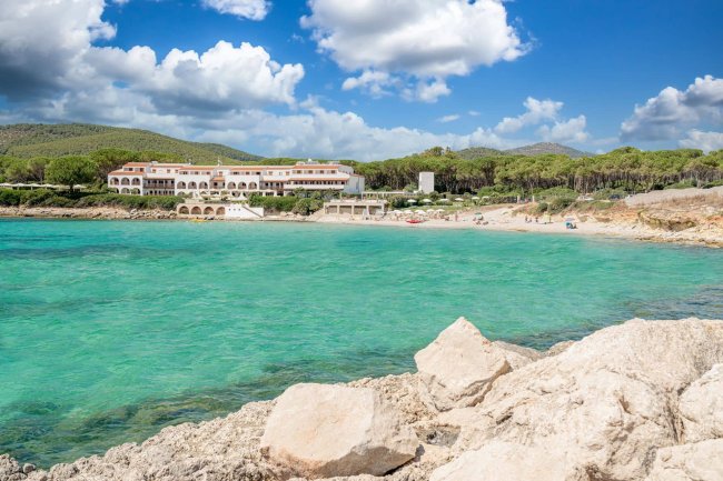 Vista su un albergo bianco davanti a una spiaggia e mare turchese.