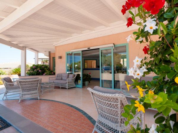 Terrazza coperta con sedie in vimini e fiori colorati.
