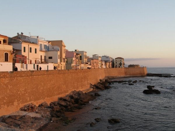 Case colorate su una muraglia lungo la costa al tramonto.