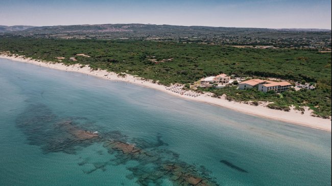 Vista aerea di una spiaggia con vegetazione densa e un resort.