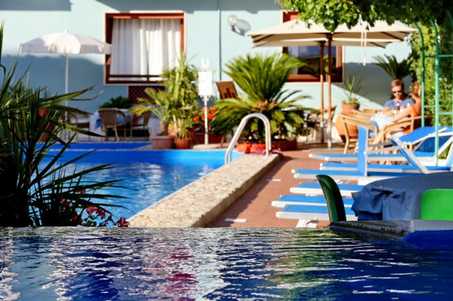Piscina con lettini blu e piante.