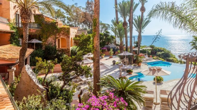 Giardino con piscina e palme vicino al mare.