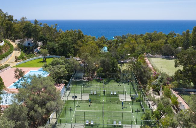 Campi sportivi con vista mare e piscina tra gli alberi.