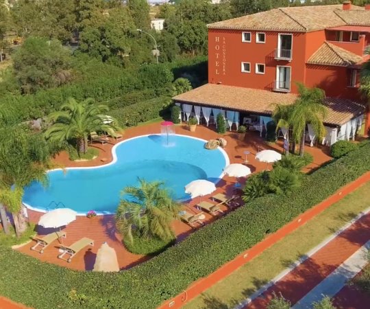 Piscina a forma libera con lettini e ombrelloni.