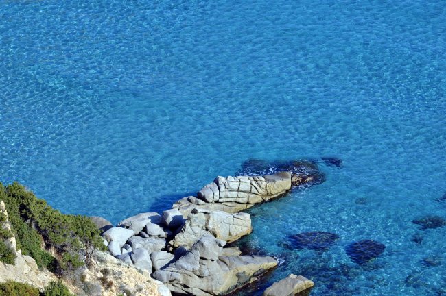 Costa rocciosa con mare blu cristallino.