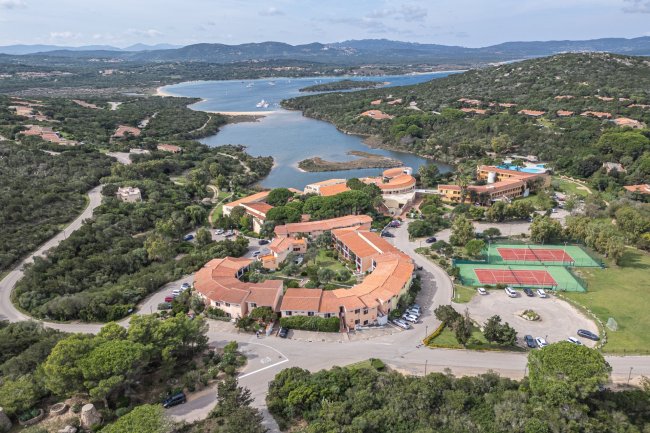 Veduta aerea di un complesso turistico con vegetazione e laguna.