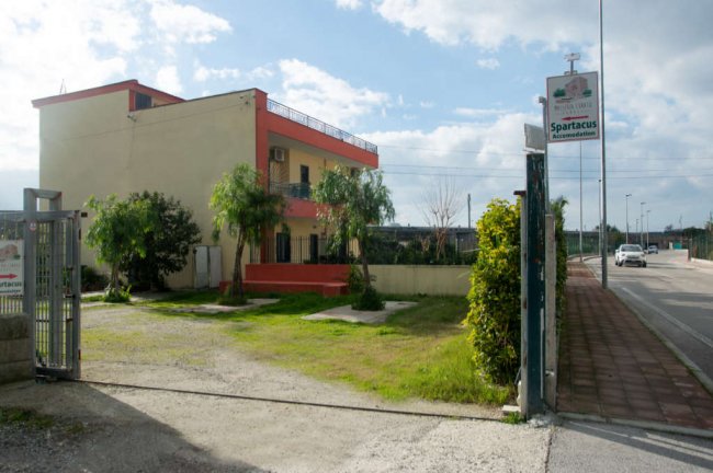 Una villa con cartello di benvenuto e giardino verde.