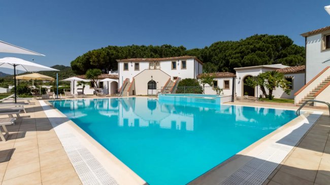 Piscina azzurra circondata da edifici bianchi.