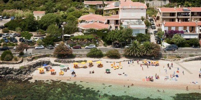 Spiaggia con ombrelloni colorati e edifici sulla costa.
