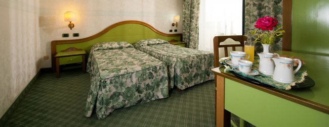 Camera con letti singoli e arredi verdi.