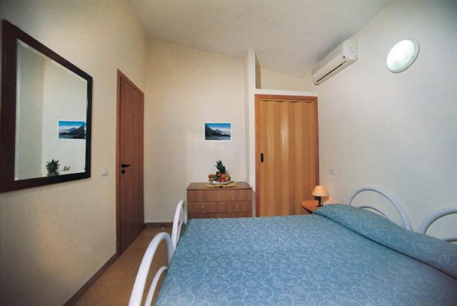 Una camera da letto con letto matrimoniale, specchio grande e aria condizionata.