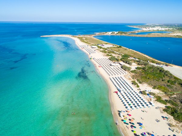 Spiaggia di sabbia bianca con ombrelloni e mare cristallino.