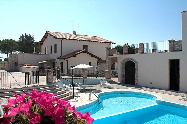 Casa con piscina e fiori rosa.