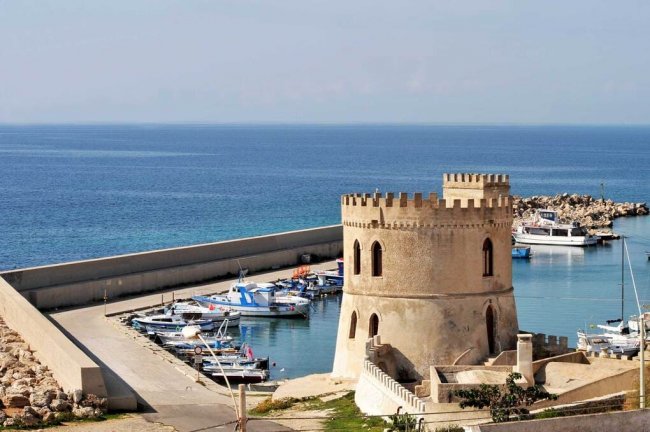 Torre storica vicino a un porto con barche.