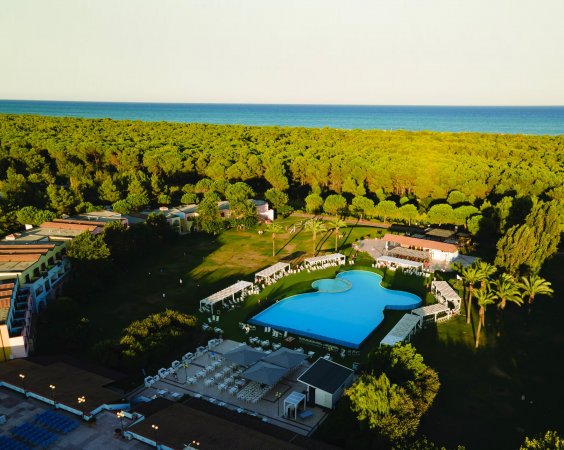 Vista aerea di un resort con piscina e foresta vicino al mare.