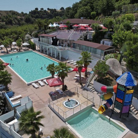 Una vista aerea di piscine con scivoli, lettini e alberi intorno.
