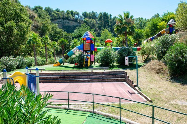Un parco giochi colorato con scivoli e altalene immerso nel verde.