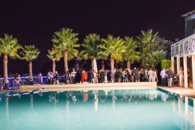 Festa notturna all'aperto vicino a una piscina, circondata da palme.